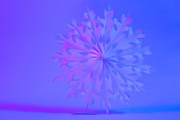 Neon Christmas winter background with paper snowflake close up.