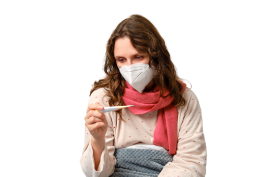 A sick woman is sitting on a bed in a medical face mask and a thermometer in her hands, isolated on a white background. Adult ill woman on a home bed in a white bedroom, female aged 35 years - Powered by Adobe