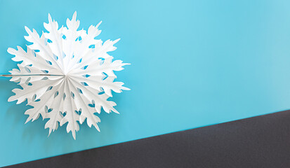 Volumetric paper snowflake on a colored background, flat lay.