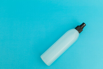 Hair spray in blue plastic bottle on blue background, monochrome