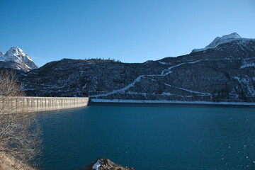 Obraz na płótnie Canvas diga, lago artificiale e montagne con neve