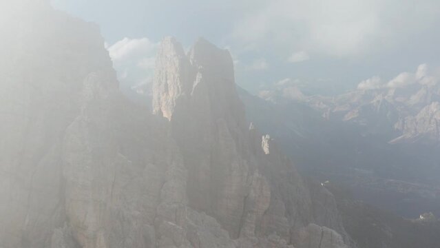 Flight through thin clouds to reveal jagged peaks of Croda da Lago mountain - epic rugged landscape in Italian Dolomites
