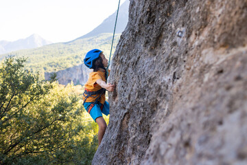 Child rock climber. The boy climbs the rock. The child is engaged in rock climbing on natural...