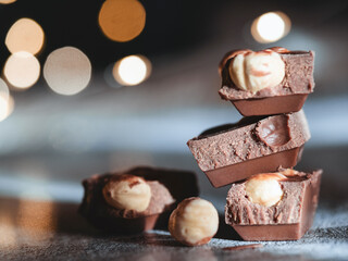 Milk chocolate with hazelnuts on a background of blurry lights. Festive food. Macro vision