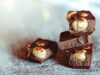 Milk chocolate with hazelnuts on a background of blurry lights. Festive food. Macro vision