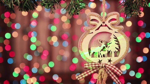 Close-up of a Christmas wooden ball with a bow on a background of glowing lights. New Year's multi-colored garlands in defocus. Holiday card with bokeh. Abstract background for captions and text. UHD