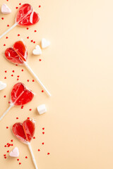 Valentine's Day concept. Top view vertical photo of heart shaped lollipops jelly candies and confetti on isolated beige background with blank space