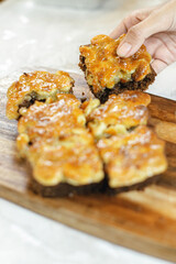 Slices of Toffee on wooden cutting board holding on hand, Delicious dessert , dessert for a cup of coffee , 
homemade bakery

