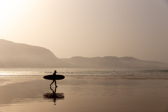 Silhouette of a surfer on the beach at beautiful sunset