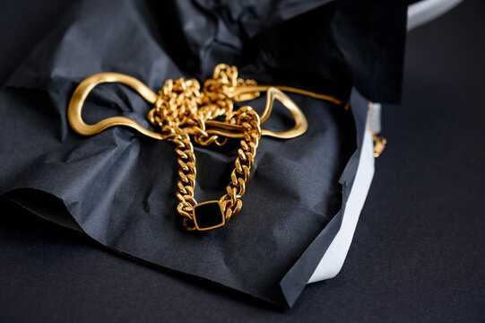 Various gold jewelry. Gold large chain. Long, wide chain on a black background.