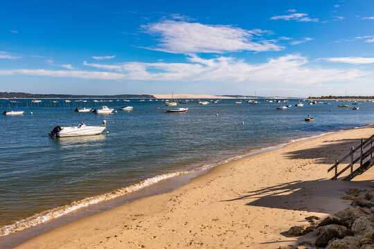 France, Nouvelle-Aquitaine, Lege-Cap-Ferret, Boats floating in Arcachon Bay with shore of Dune of Pilat in foreground