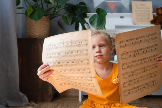 Cute girl reading musical notes at home
