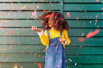 Girl playing with confetti in front of wall
