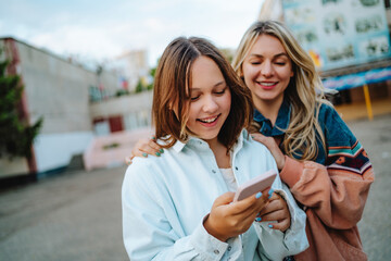 Smiling mother with daughter using mobile phone
