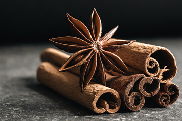 Aromatic cinnamon sticks and anise on black table, close up.