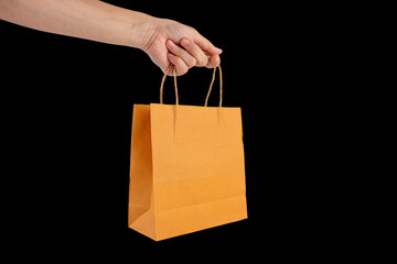 Hand Holding Paper Bag isolated on black background.