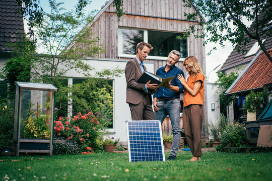 Happy Mature Couple Having Discussion With Real Estate Agent In Back Yard