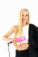Hairdressing. Woman with beautiful long straight blond hair using a hair straightener. Gorgeous smiling girl straightens her healthy blond hair with a straightening iron