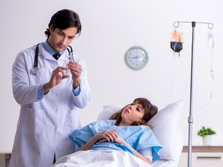 Male doctor visiting female patient in ward