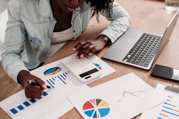 Freelancer preparing statistics using calculator on desk at home office