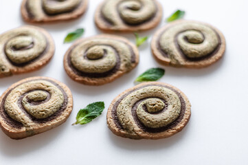 Mint - chocolate biscuits in the form of snails on a white background with mint leaves closeup.