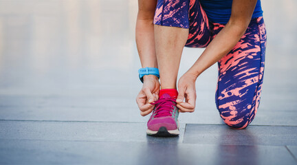fitness woman tie shoelaces on road. Female runner wearing sport shoes. Active woman tying shoe lace before running