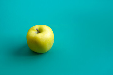 Yellow apple on a blue background. Healthy food. Place for text.