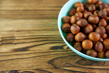 Hazelnut close-up in blue plate on wooden background with space for text.