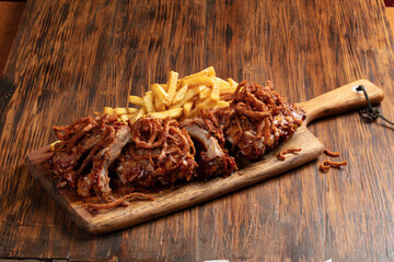 Costillar con salsa barbacoa sobre tabla de madera y patatas fritas. Ribs with barbecue sauce on wooden board and french fries.