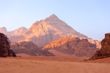 Fototapeta na wymiar Wadi Rum, Jordan. The orange sand desert landscape and Jabal Al Qattar mountains at dawn, sunset