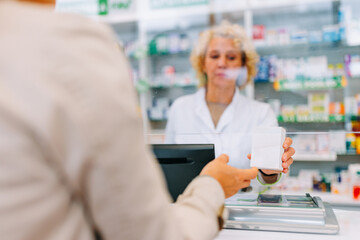 Close up of pharmacist handing medication to customer.
