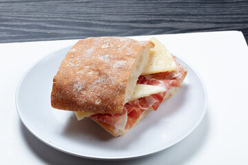 Baguette de jamón ibérico y queso curado sobre fondo blanco. Iberian ham and cured cheese baguette on white background.