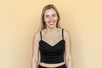 Fototapeta premium Portrait of happy young woman with freckles posing against beige background. Beautiful female model smiling