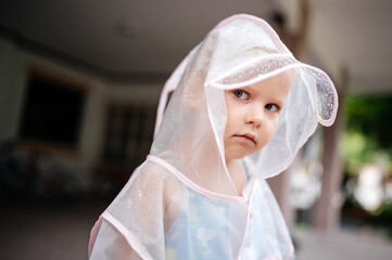 Portrait of a sad child in a raincoat outdoors. Bad mood when it rains.