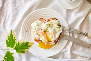 Top view Breakfast on white bed sheets, good morning, toast with poached eggs, coffee, flowers, Hotel room early morning, honeymoon