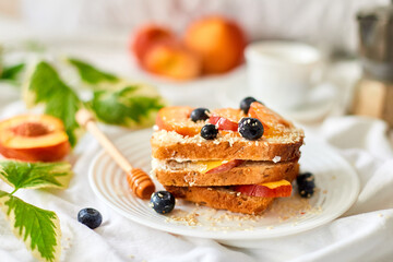 Breakfast on white bed sheets, good morning, summer french toast with cream cheese, honey, peaches and blueberries, coffee, flowers, Hotel room early morning, honeymoon