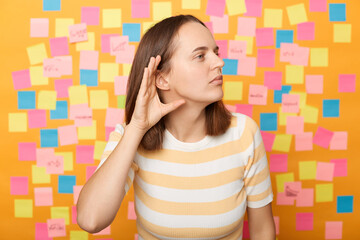 What? I can't hear you. Confused woman standing isolated over yellow background with memo cards, keeping hand near ear to listen better, having hearing problems, difficult to understand. - Powered by Adobe