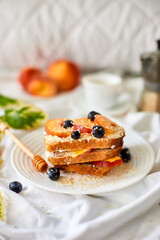 Breakfast on white bed sheets, good morning, summer french toast with cream cheese, honey, peaches and blueberries, coffee, flowers, Hotel room early morning, honeymoon