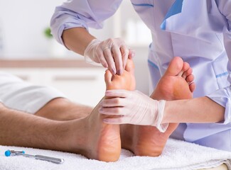 Podiatrist treating feet during procedure - obrazy, fototapety, plakaty
