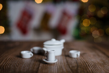 Miniature tea set on wooden table. Background with Christmas decorations.