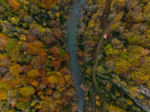 Casa al lado del rio en un bosque en otoño vista aérea