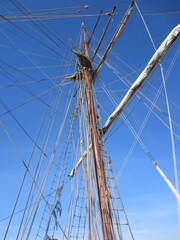 Mast of an old sailing ship with a folded sail and ropes