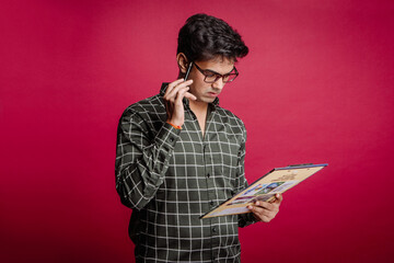 A man in glasses thinking or recollecting with a pen and a clipboard in his hand.