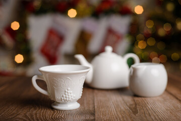 White tea set with embossed engraving on wooden table with Christmas background.