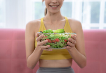 Happy Caucasian woman eating fresh salad from a bowl.