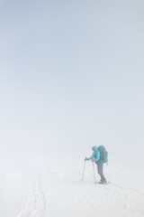 girl with a backpack and snowshoes walks through the snow during a snow storm.