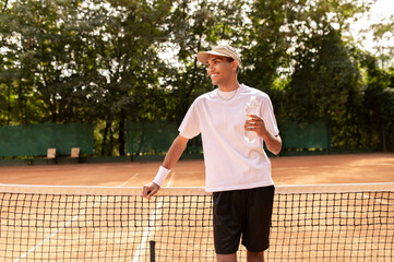 Young man in white thsirt standing at the tennis court