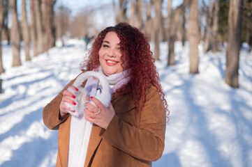Cheerful fat caucasian woman in fur headphones outdoors. 