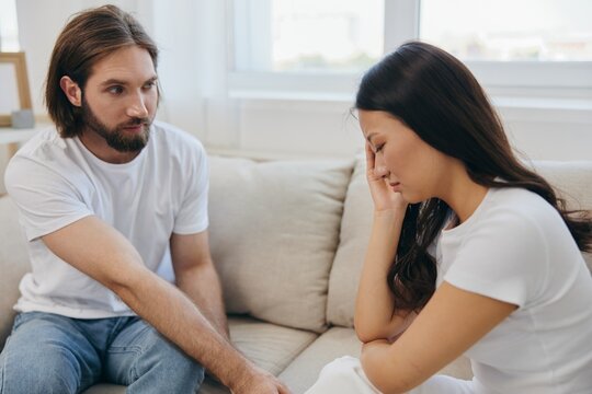 An Asian woman is sad and crying with her male friend at home. Stress and misunderstanding in a relationship between two people and supporting each other's mental and emotional well-being