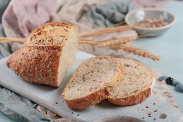 Sliced fresh baked whole grain bread with flax seeds and sesame seeds on light blue board. Bakery products